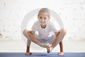 Girl child in Bhuja Pidasana pose, white studio background