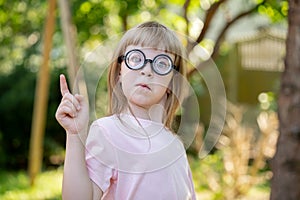 Girl, child with big large funny glasses pointing her finger upwards, eureka gesture, coming up with an idea. Smart intelligent
