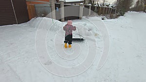 Girl child cleans snow with a shovel worker assistant