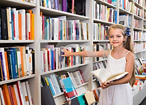 Girl child considers the book in a bookstore