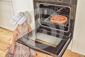 The girl child cooks pizza in the oven photo without filter