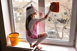 Girl child detergent with rag cleaning house, washing windows, springtime