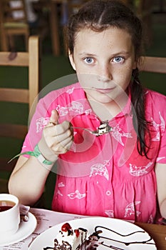 Girl child eating cake in cafe