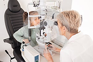Girl child in eye exam for vision, woman optician checking kids eyes in consultation room and medical test. Healthcare