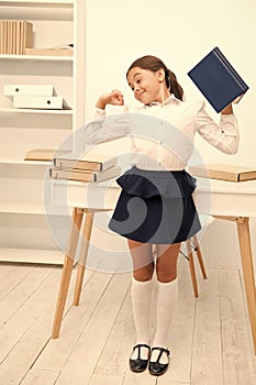 Girl child hold book while stretching white interior. Kid school uniform making exercise stretching increase