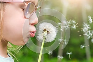 Girl child holds and blows on a dandelion. Happy childhood concept. Playing outdoors