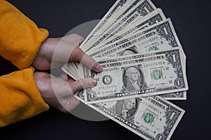 Girl child holds many American dollars paper money in her hands.