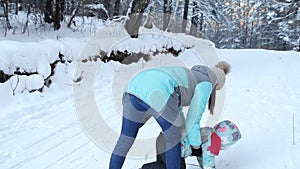 Girl child is learning to ski. She slowly slides on skis in soft fresh snow. Beautiful day in the winter forest. Woman