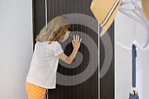 Girl child looking in the peephole at the front door