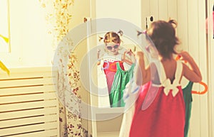 Girl child looks into the mirror and choose dresses