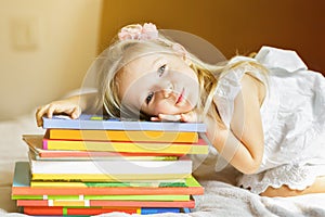 Girl child lying on the bed with books. Kid prepare to go to bed. Pleasant time in cozy bedroom. Girl kid relax and read book.