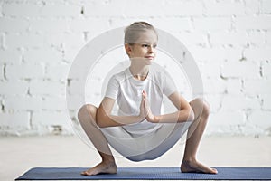 Girl child in Malasana pose, white studio background