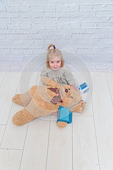 Girl, child measures the pressure of the toy bear, plays doctor