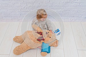 Girl, child measures the pressure of the toy bear, plays doctor