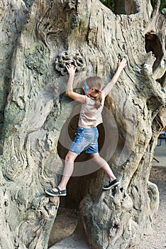 Girl child outdoors climb tree with butterfly face painting