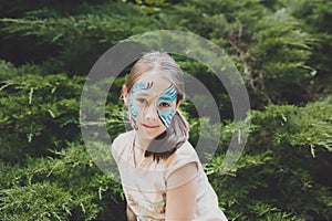 Girl child outdoors in park with butterfly face painting
