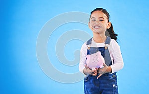 Girl child, piggy bank and studio portrait with mockup space, saving and financial education by blue background. Female