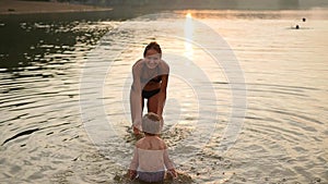 The girl and the child playing in the sea, creating a splash of water. Fun and games in the fresh air. Sunset time