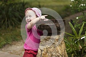 Girl child playing with small fountain bubbler in the park