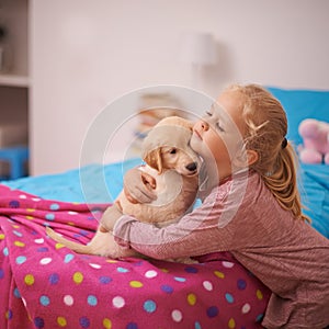 Girl, child and puppy with hug on bed for playing, bonding and protection in bedroom of home with love. Kid, golden