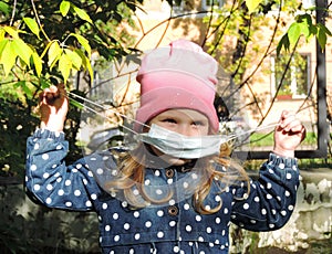 Girl child  puts on  a medical mask and walking in the park.