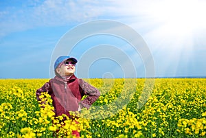 Girl child in rapeseed field with bright yellow flowers, spring landscape