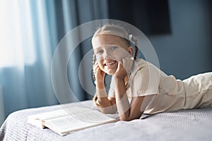 Girl child reads a book in the room