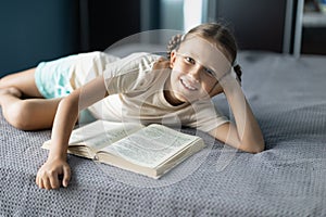 Girl child reads a book in the room