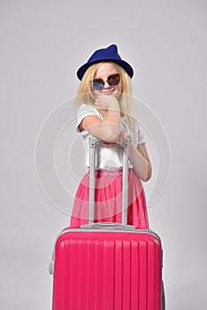 Girl child ready to travel and posing with a pink suitcase
