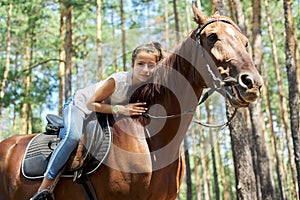 Girl child riding horse, summer horse ride in the forest, girl lovingly hugged horse