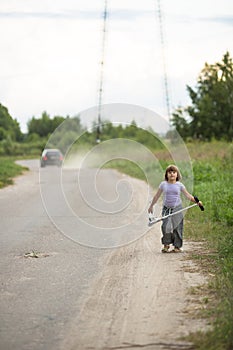 Girl child riding scooter near car on road In countryside, ch