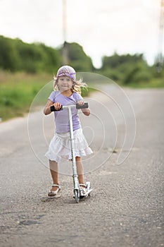 Girl child riding scooter on the road In the countryside, child