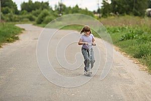 Girl child riding scooter on the road In the countryside, child