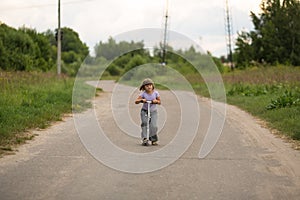 Girl child riding scooter on the road In the countryside, child