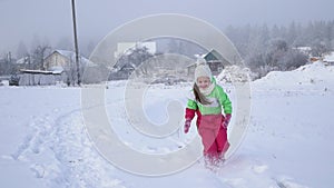 Girl child runs on snow-covered road. Active holidays for children A cloudy winter day.