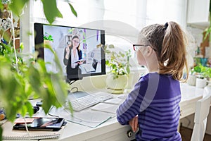 Girl child studying at home using a computer for video lesson