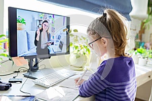 Girl child studying at home using a computer for video lesson