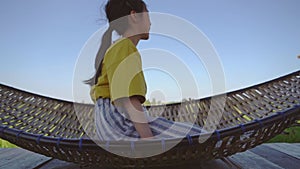 Girl child is swinging on a Hammock in a country house surrounded by paddy rice field for nature relaxing cocnept.