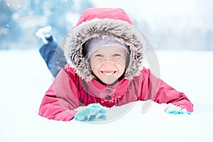 Girl child in warm clothes red pink jacket playing with snow having fun during cold winter snowy