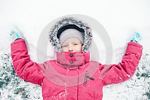 Girl child in warm clothes red pink jacket playing with snow having fun during cold winter snowy