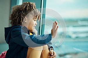 Girl child, wave and airport window for greeting, goodbye and smile for airplane, international transport and travel