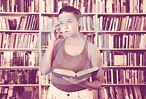 Girl chooses a book in the library