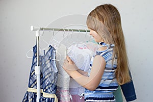 A girl chooses clothes from a hanger from wardrobe