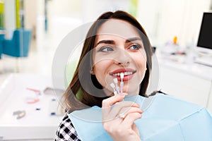 Girl chooses color of veneers at the dentist office