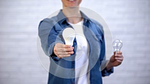 Girl chooses energy saving led bulb instead of incandescent lamp, efficiency