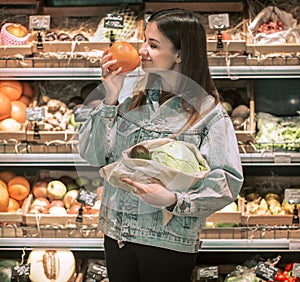 girl chooses fruits and vegetables in the store and puts them in eco bag