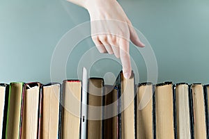 Girl chooses an old paper book instead of a tablet, which stands next to