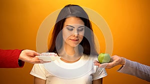 Girl choosing apple instead of donut, natural sugar and vitamin vs confectionery