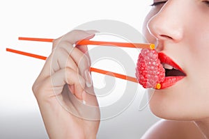 Girl with chopsticks and raspberry