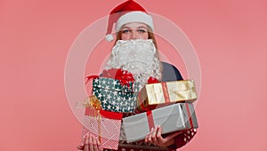 Girl in Christmas fake beard of Santa Claus surprised of present boxes excited by many holiday gifts